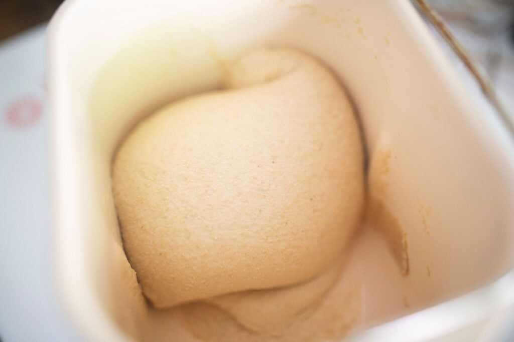 A perfectly kneaded dough ball in a cream colored pan.