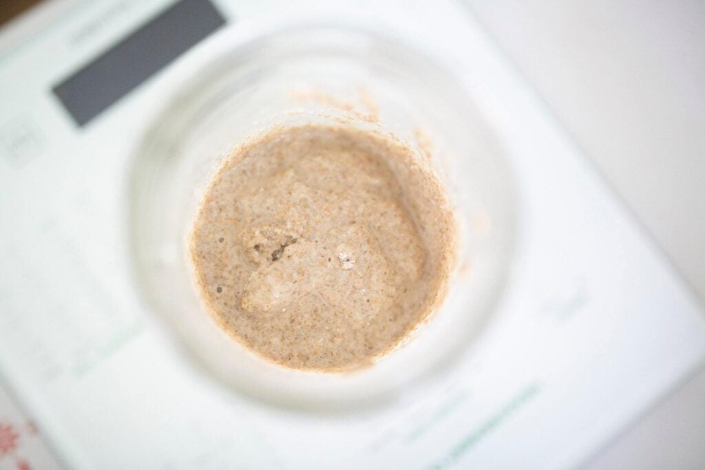 Overhead photo of sourdough starter in a jar sitting on a kitchen scale.