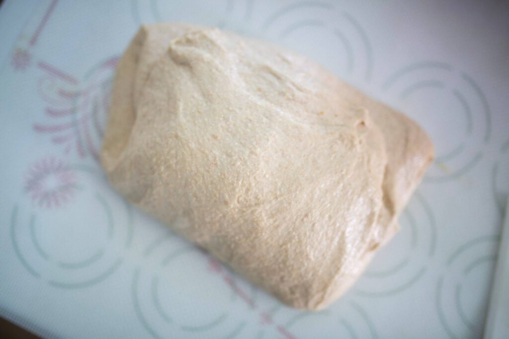 Bread dough sits on a silicone mat before shaping.