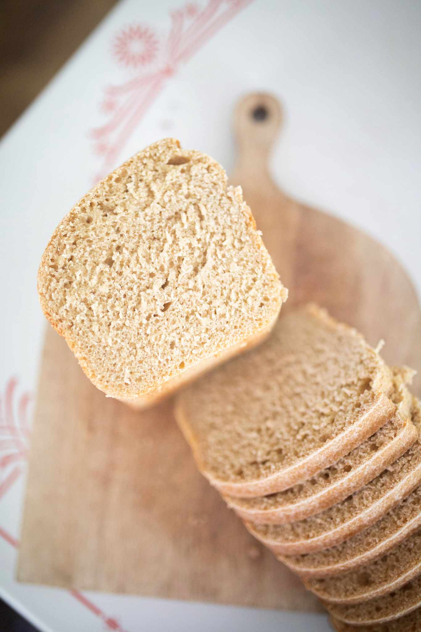 Half a loaf of bread is laying crumb side up on a cutting board with several slices laid out in front of it.