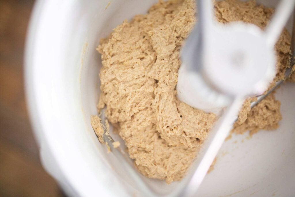 Bread dough is in the stand mixer before kneading. It is a rough dough.