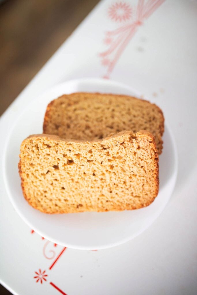 2 slices of bread are on a white plate sitting on a white table top.