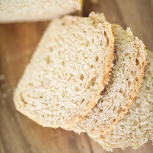 3 slices of sandwich bread on a cutting board are laying on top of each other.