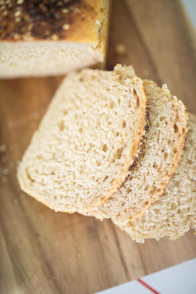 3 slices of sandwich bread on a cutting board are laying on top of each other.