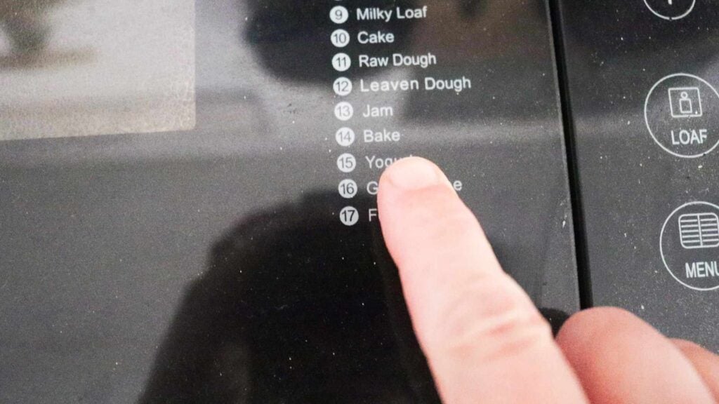 Finger pointing to the bake function on a machine.