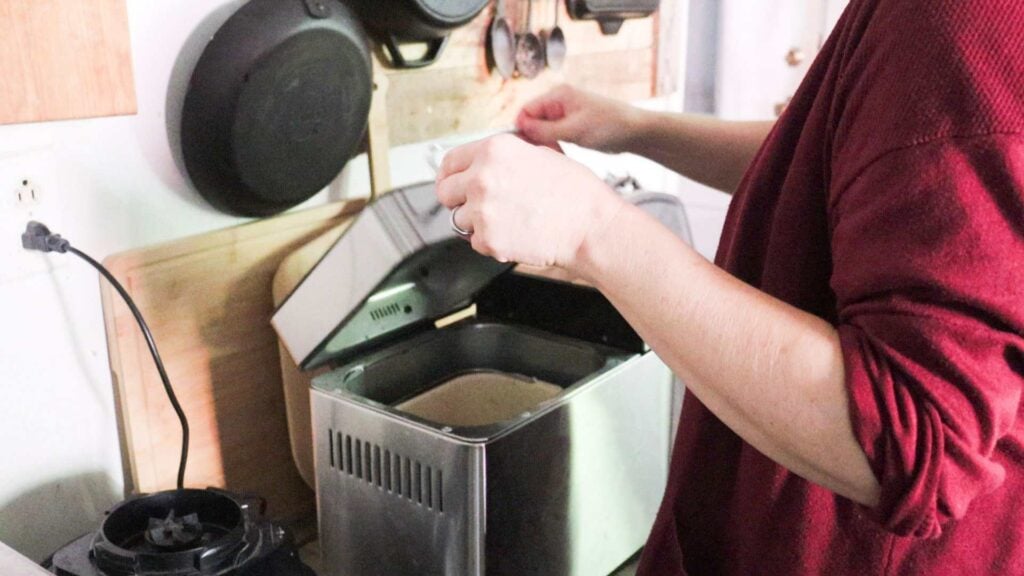 Lady closing the lid on a bread machine.