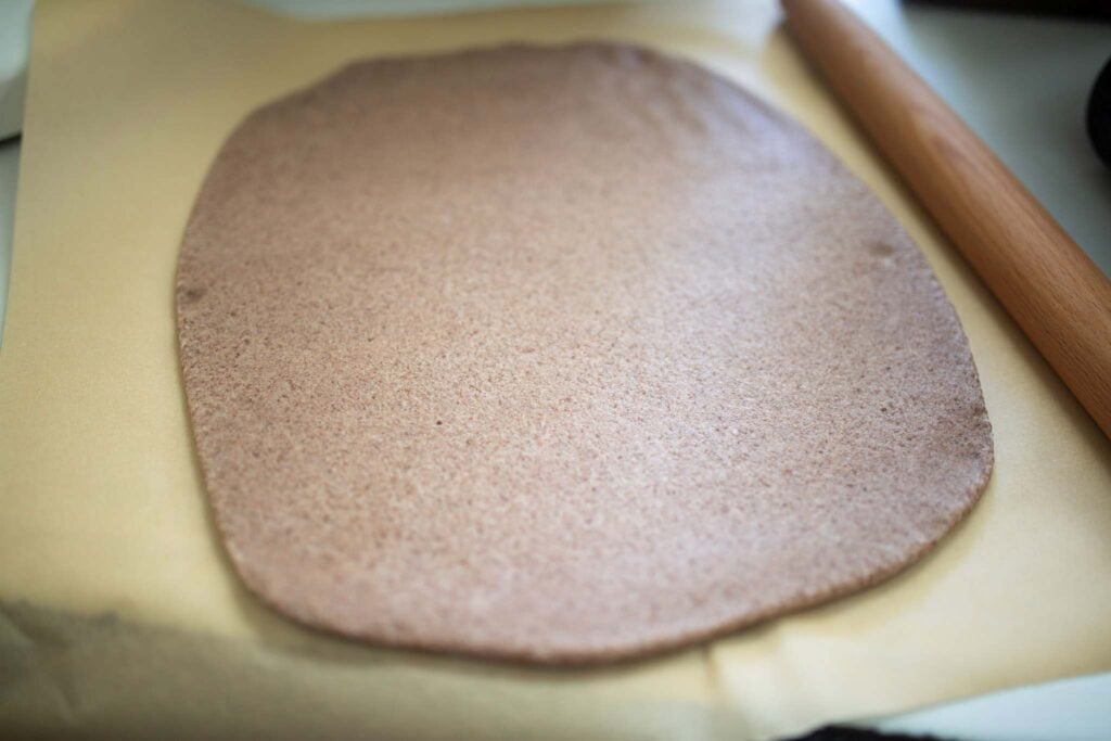 Breadstick dough is rolled out on a piece of parchment paper.