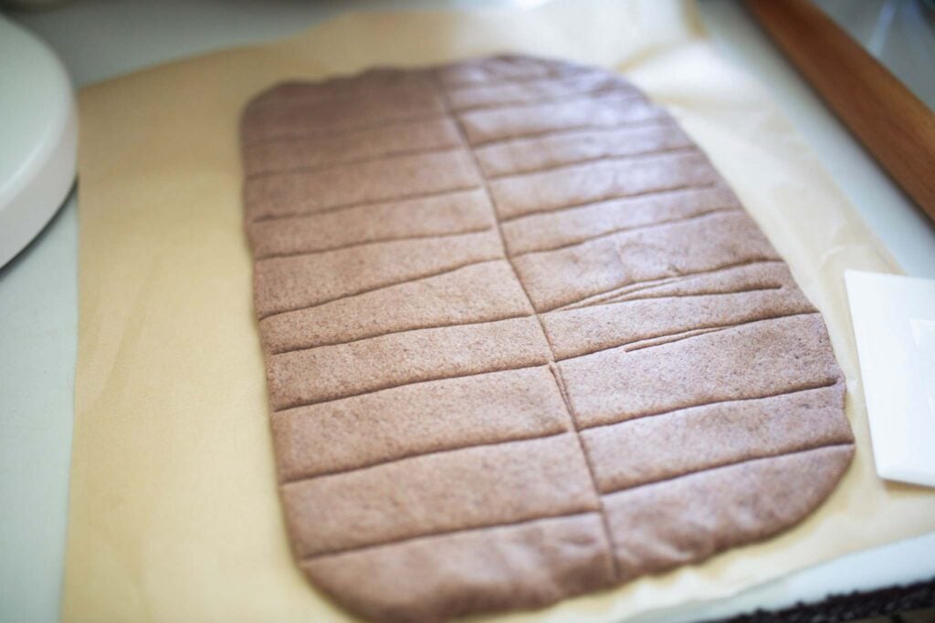 breadstick dough is scored into breadsticks on a piece of parchment paper.