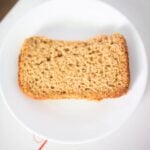 A slice of sandwich bread sits on a white plate on the kitchen table.