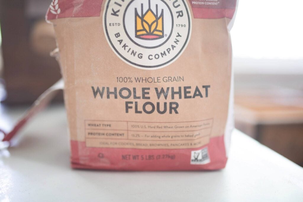 This is a bag of whole wheat flour sitting on a white counter top.