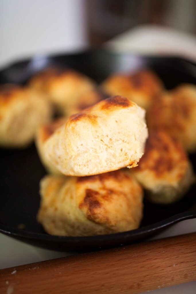 Close up of the side of a biscuit sitting on other biscuits to show the crumb.