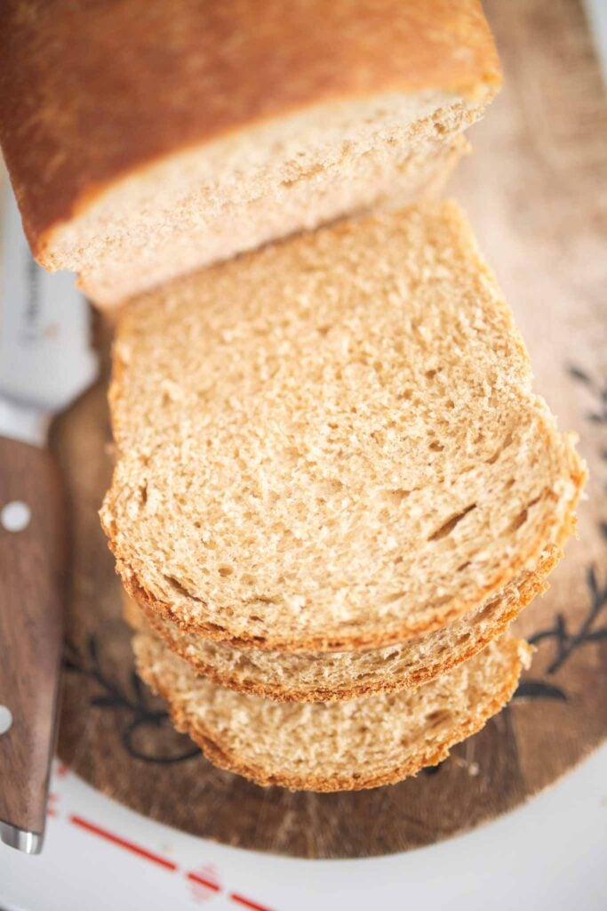 An overhead photo of a loaf of sandwich bread with a few slices on a cutting board.