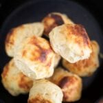 An overhead photo of a pile of biscuits in a cast iron skillet.