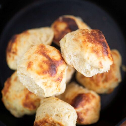 An overhead photo of a pile of biscuits in a cast iron skillet.