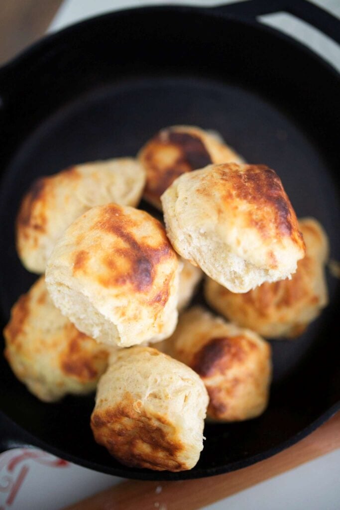 An overhead photo of a pile of biscuits in a cast iron skillet.