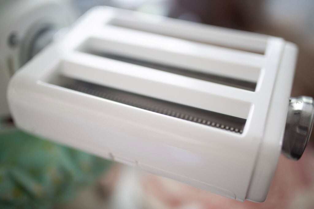 A pasta maker attachment. It is white with 3 different slots.