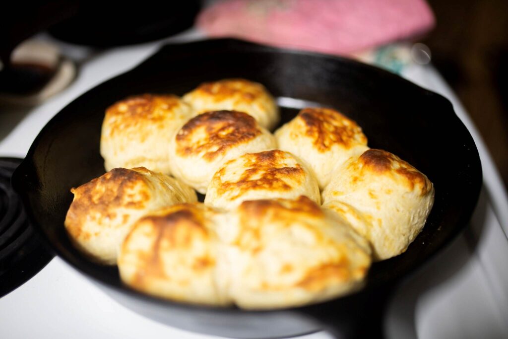 A side view of sourdough biscuits in a cast iron skillet.