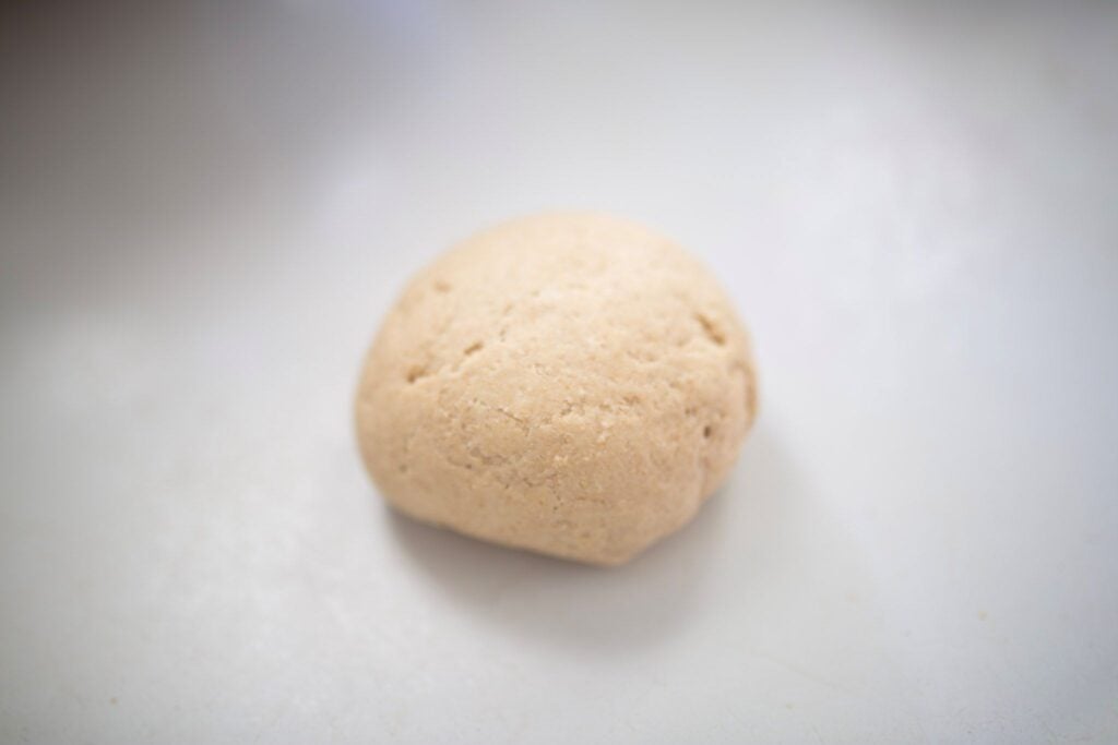 A ball of dough sits on a white counter.