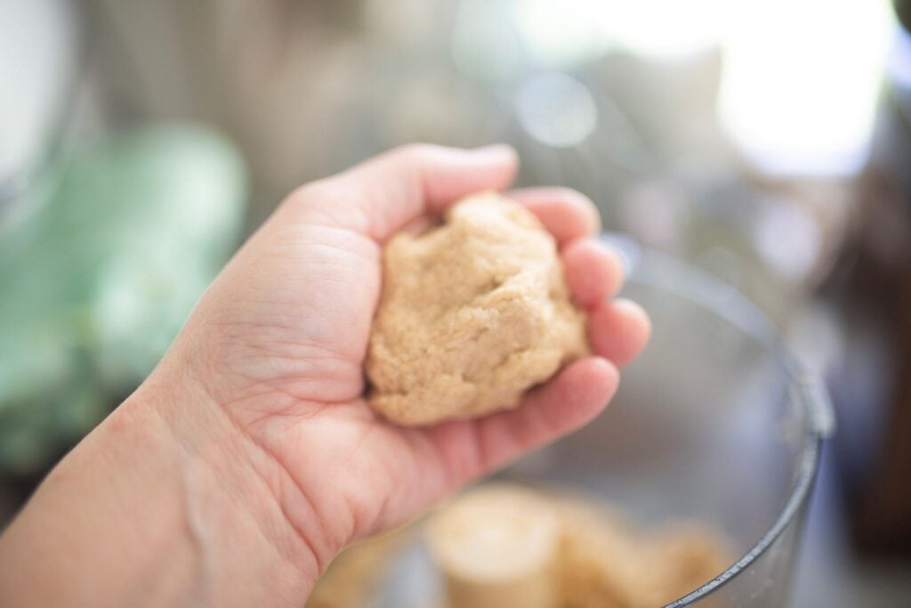 A hand is holding a ball of dough.