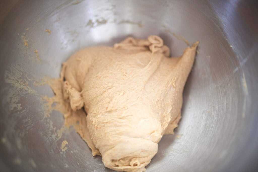 This is a stainless steel bowl with bread dough that has been kneaded.