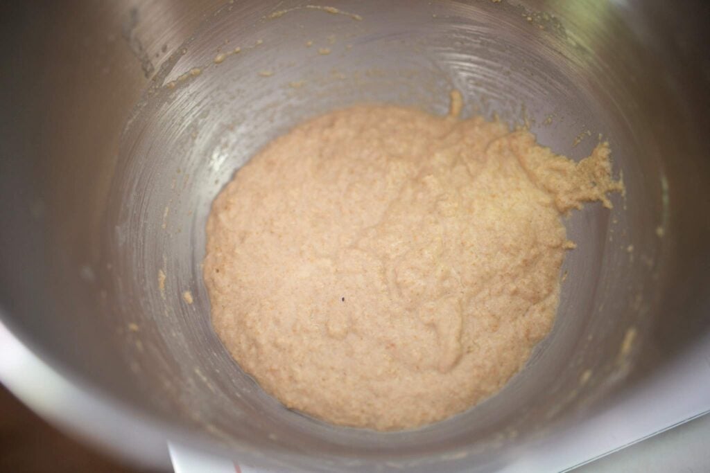 Bread batter for a sponge is in a stainless steel bowl.