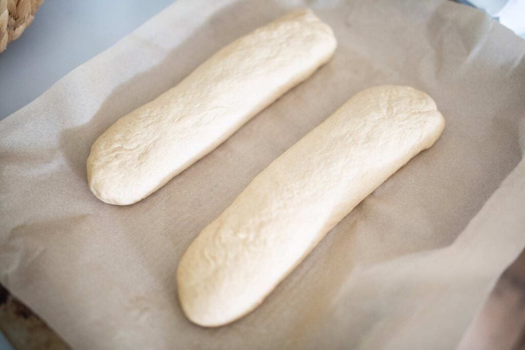 2 shaped logs of dough on a piece of parchment paper.